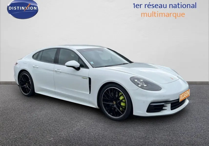 Vue 3/4 avant gauche d'une Porsche Panamera 4 E-Hybrid blanche avec jantes sport noires et étriers verts.