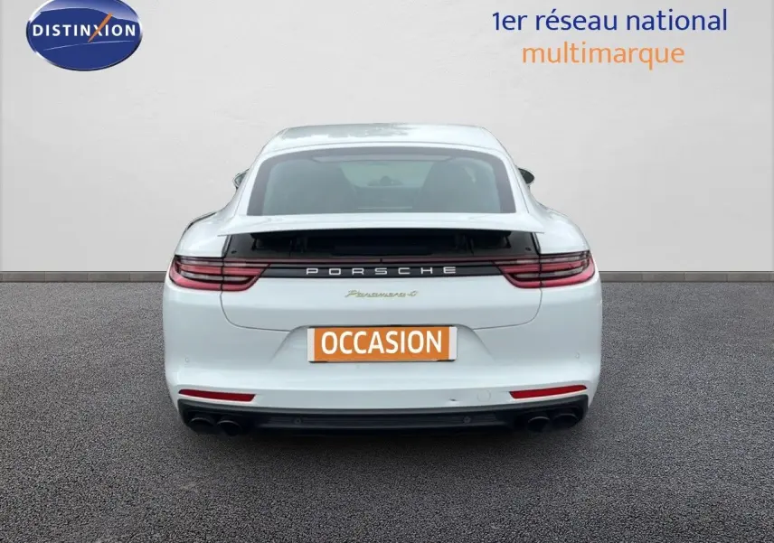 Vue arrière d'une Porsche Panamera 4 E-Hybrid blanche avec sorties d’échappement sport noires et feux LED étirés.