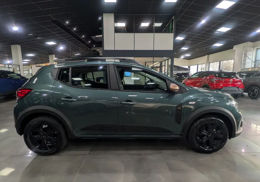 Vue latérale droite d'une Dacia Sandero Stepway TCe 110 CH Extreme vert cèdre avec jantes noires en showroom.