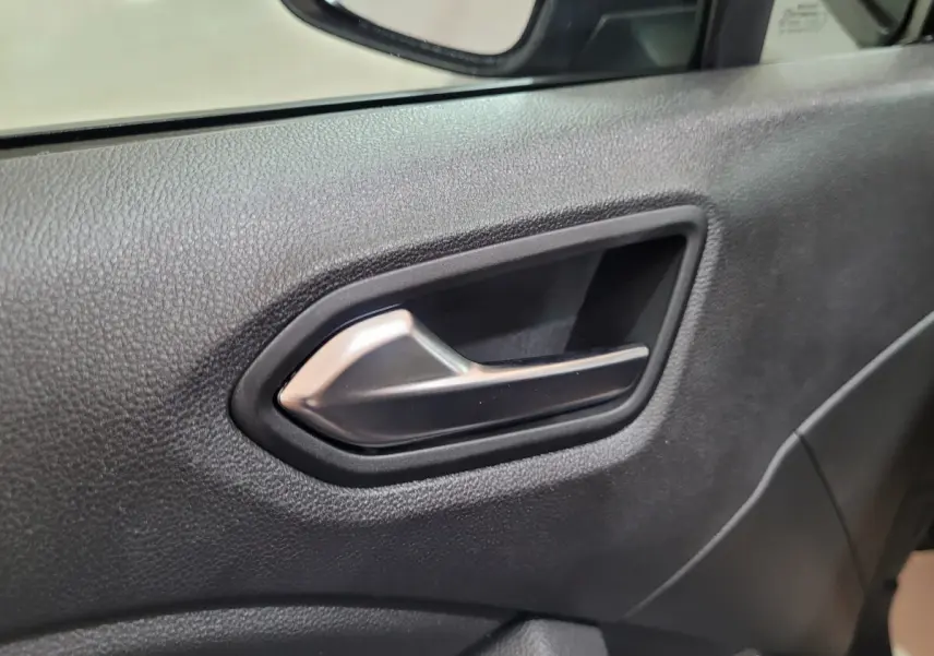 Poignée intérieure côté gauche de la porte d'une Renault Clio gris foncé, avec texture noire et miroir partiel visible.