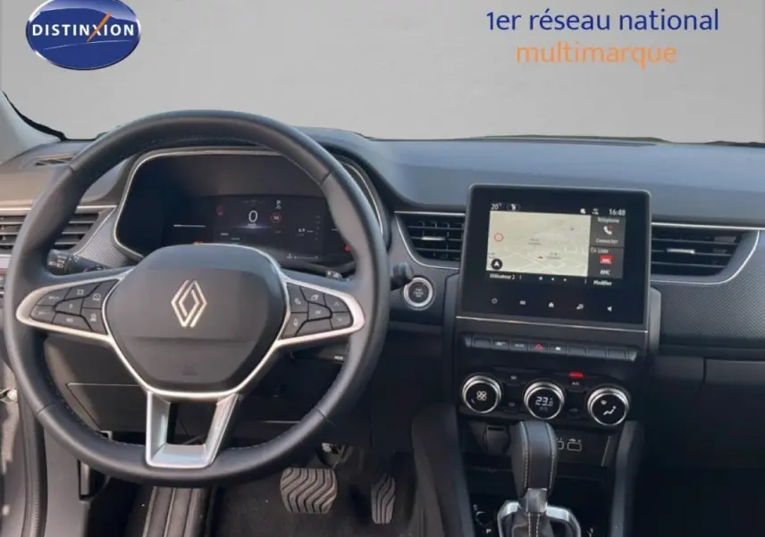 Vue intérieure centrée sur le volant cuir et l’écran tactile du tableau de bord du Renault Arkana gris 2025.