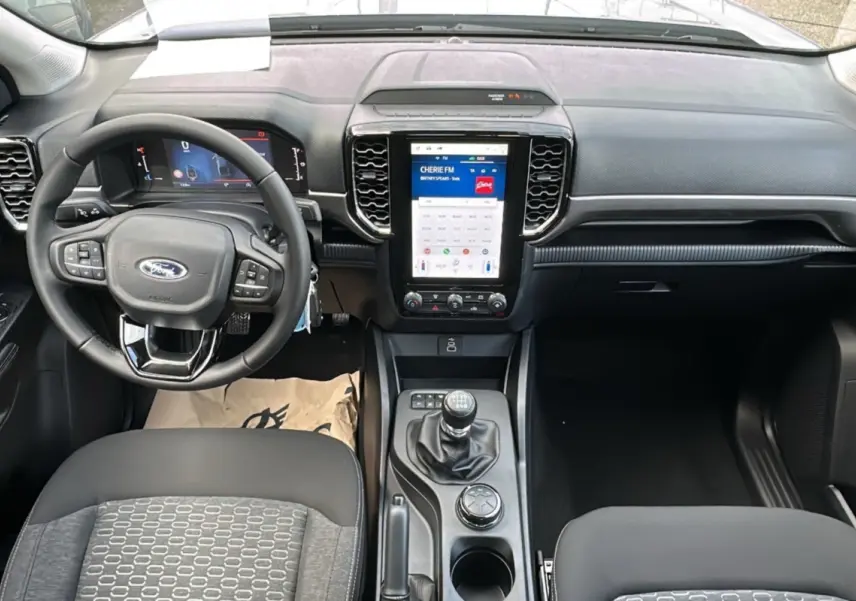 Vue intérieure du tableau de bord et console centrale du Ford Ranger 2026 avec volant multifonctions et écran tactile vertical.