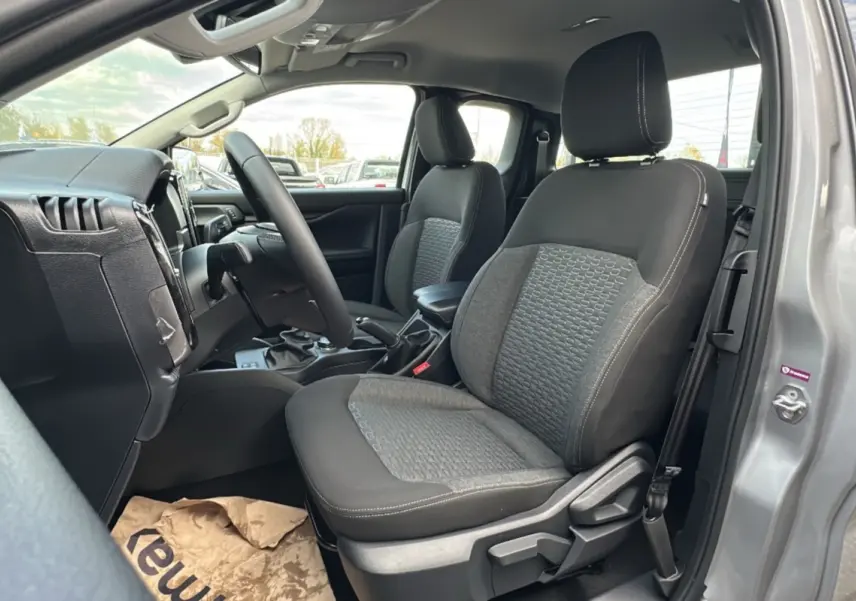 Vue intérieure côté conducteur du Ford Ranger gris iconic 2026, montrant les sièges avant en tissu et le volant multifonctions cuir.
