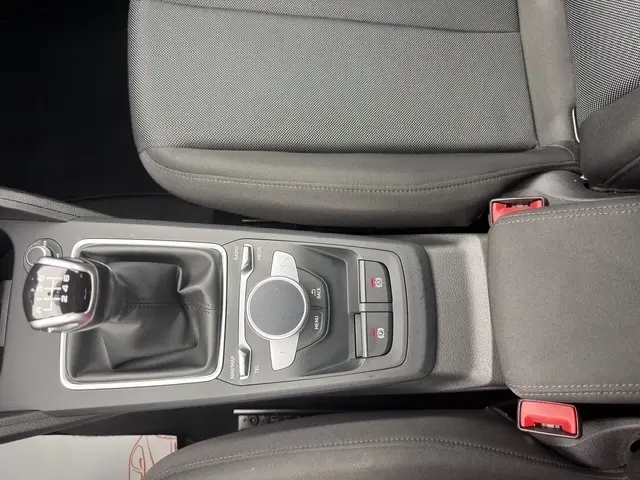 Vue plongeante sur la console centrale noire de l'Audi Q2 30 TDI 116 Design avec boîte manuelle et commandes multimédias.
