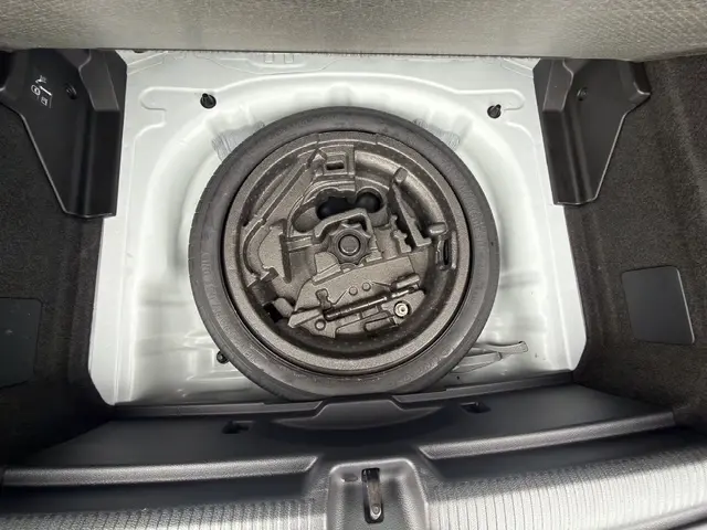 Vue plongeante sur la roue de secours et les outils de bord dans le coffre blanc de l'Audi Q2 30 TDI 116 Design 2021.