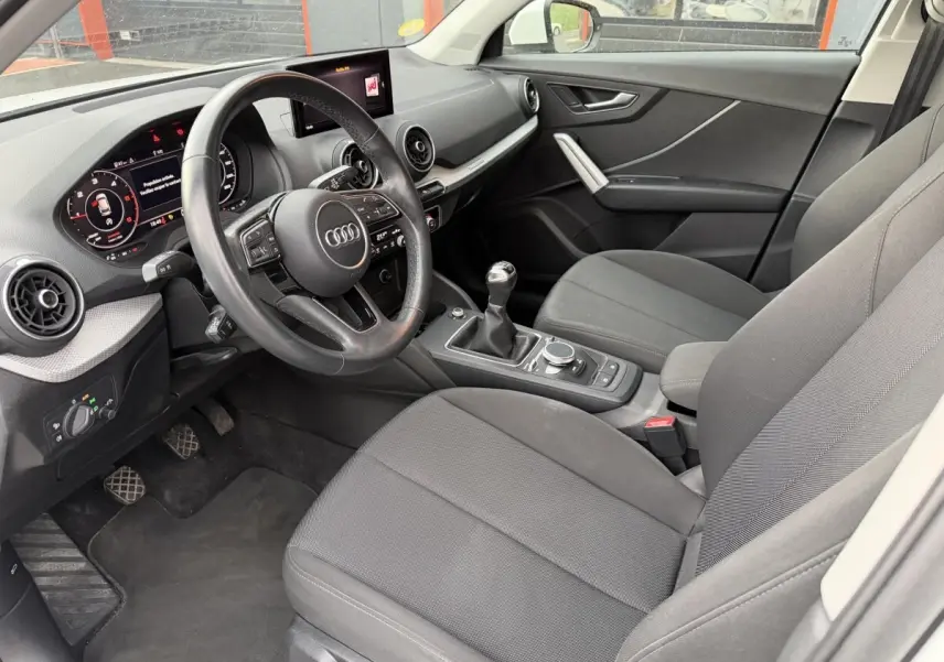 Gros plan sur la roue avant gauche d’un Audi Q2 blanc 2021 avec jante en alliage au design moderne.