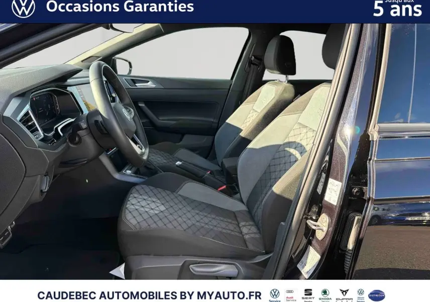 Vue intérieure côté conducteur de la Volkswagen Polo noire intense nacrée, mettant en valeur les sièges avant et le tableau de bord.