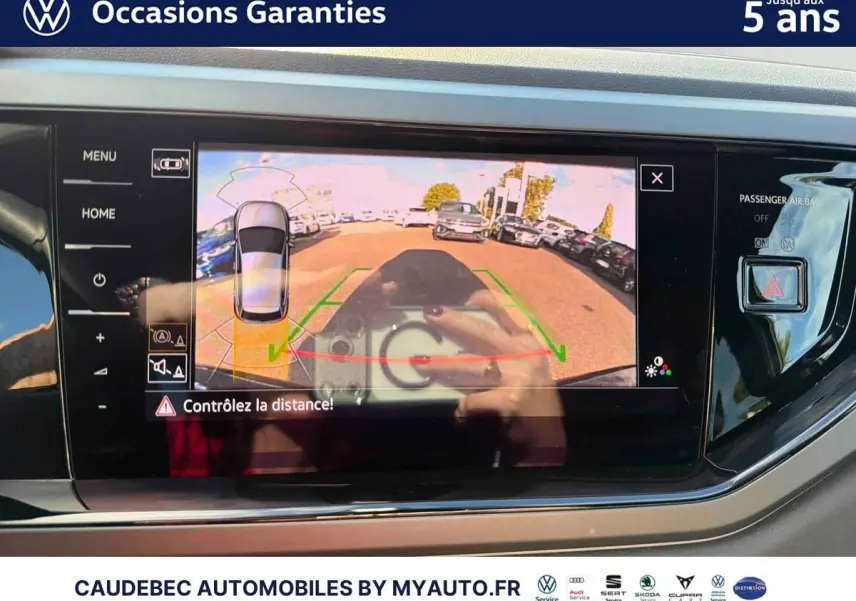 Écran tactile intérieur montrant la caméra de recul d'une Volkswagen Polo noire intense nacrée, vue arrière en stationnement.