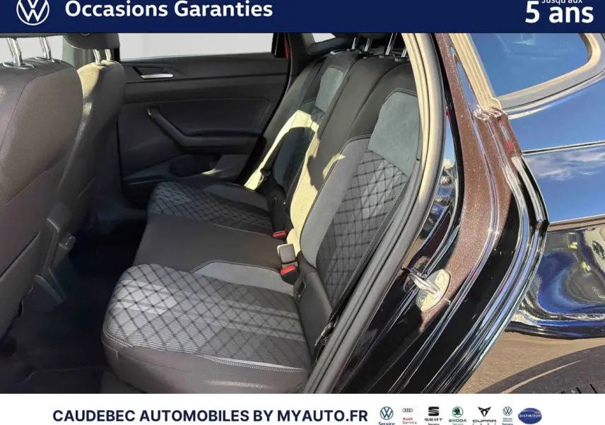 Vue côté droit sur l'intérieur arrière de la Volkswagen Polo noir intense nacré, montrant la banquette avec sellerie bicolore et motifs géométriques.