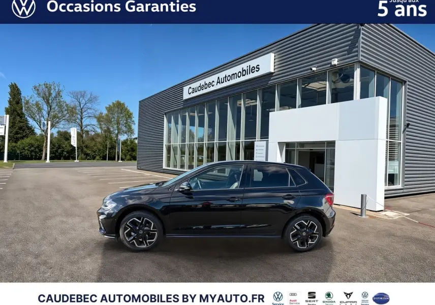 Vue latérale droite d'une Volkswagen Polo noire intense nacrée stationnée devant un bâtiment moderne en verre.