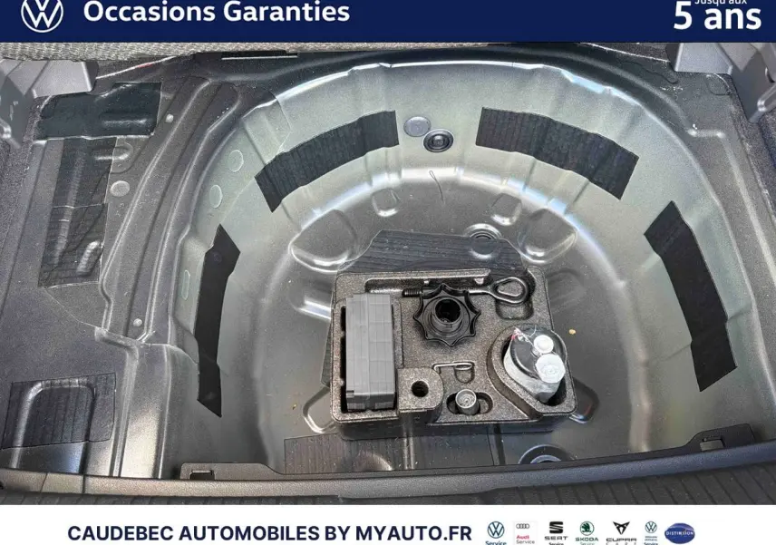 Vue plongeante sur le coffre de la Volkswagen Polo noire intense nacrée, montrant le rangement sous plancher avec outils.
