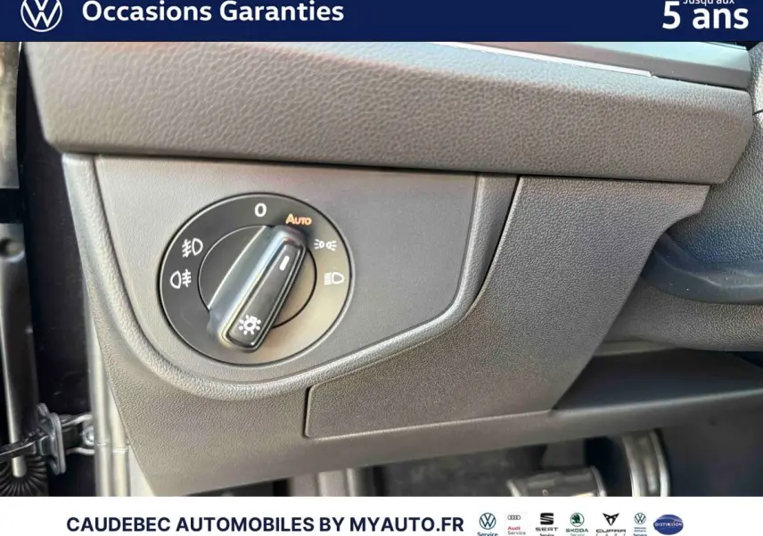 Détail du bouton de commande des phares sur tableau de bord gris foncé d’une Volkswagen Polo noire.