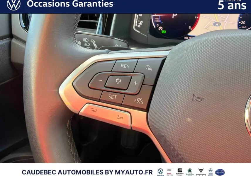 Gros plan sur les commandes du volant cuir de la Volkswagen Polo noire, mettant en valeur les boutons du régulateur de vitesse.