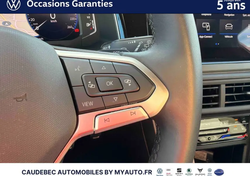 Gros plan sur le volant multifonctions en cuir et la partie droite du tableau de bord tactile de la Volkswagen Polo noire.