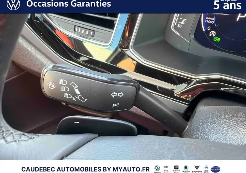 Gros plan sur la manette de clignotants noire et le tableau de bord digital de la Volkswagen Polo noire intense nacrée.