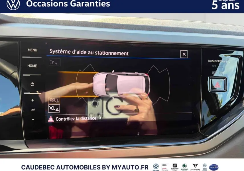 Écran tactile intérieur affichant le système d'aide au stationnement d'une Volkswagen Polo noire, vue de face.