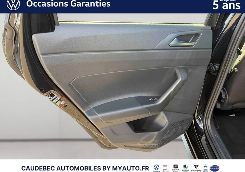 Vue rapprochée de la porte arrière gauche d'une Volkswagen Polo noire intense nacrée, montrant la garniture intérieure grise.