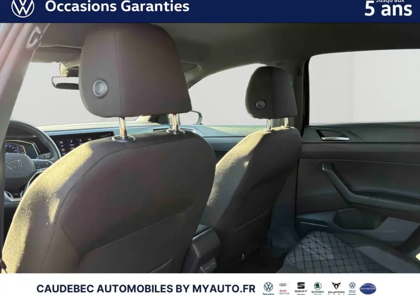 Vue intérieure arrière de la Volkswagen Polo 2026, sièges noirs et tableau de bord moderne visible côté droit.