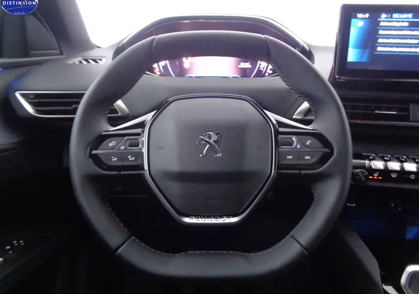 Vue rapprochée du volant cuir noir du Peugeot 3008 2023, avec commandes intégrées et tableau de bord digital.