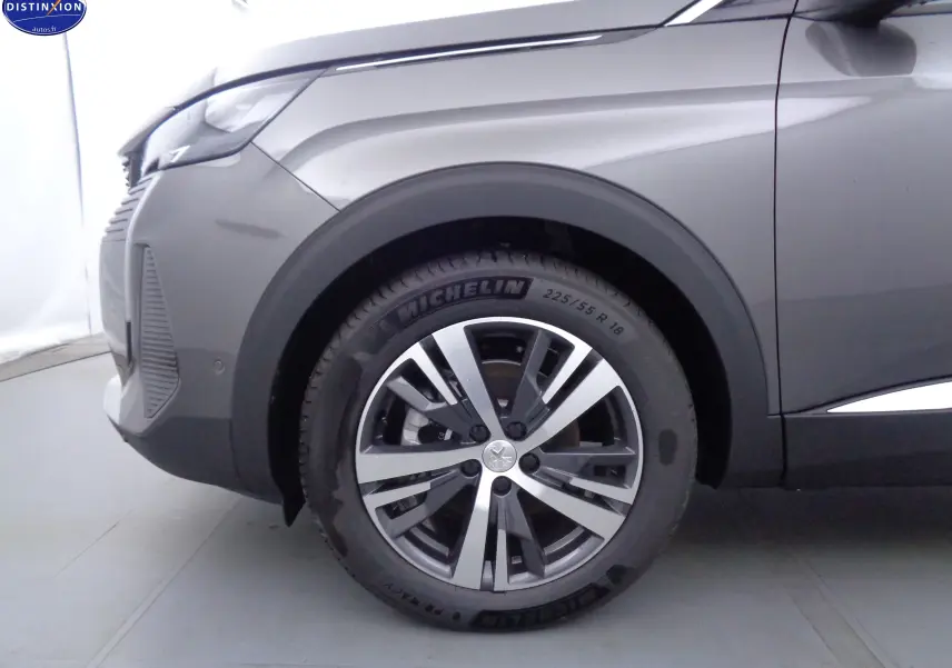 Gros plan sur la roue avant gauche et l'aile d'un Peugeot 3008 gris platinium métal, soulignant la jante alliage et le pneu Michelin.