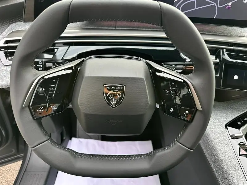 Volant cuir multifonction avec logo Peugeot en gros plan dans l'habitacle du 3008 gris Titane 2025