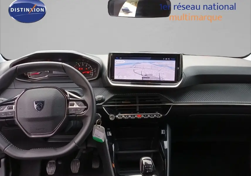 Vue intérieure du tableau de bord et volant de la Peugeot 208 gris Artense, avec écran tactile et boîte manuelle.