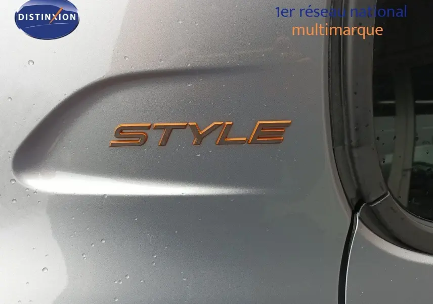 Détail de l’inscription STYLE en orange sur la porte arrière droite d’une Peugeot 208 gris Artense métal.