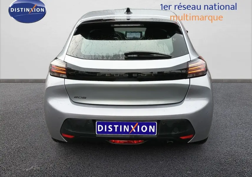 Vue arrière d'une Peugeot 208 gris Artense métal 2025 avec feux LED et hayon fermé sur sol goudronné.