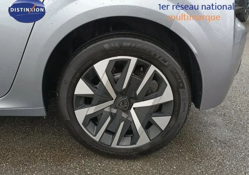 Gros plan sur la roue avant droite d’une Peugeot 208 gris Artense métal avec jante alliage au design géométrique.