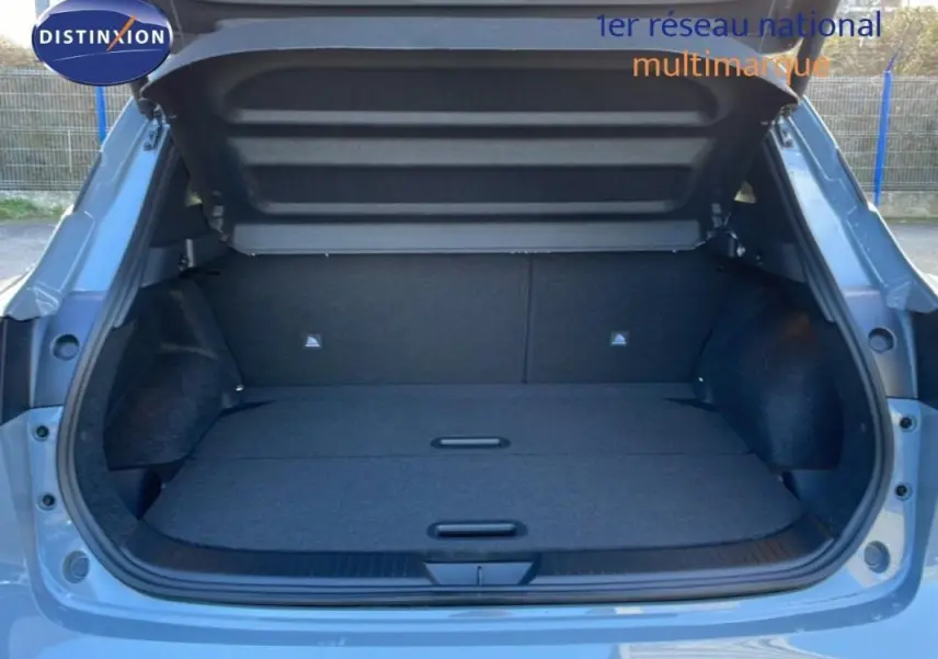 Coffre ouvert vu de l'arrière d'un Nissan Qashqai gris 2025, montrant un espace de chargement plat et spacieux.