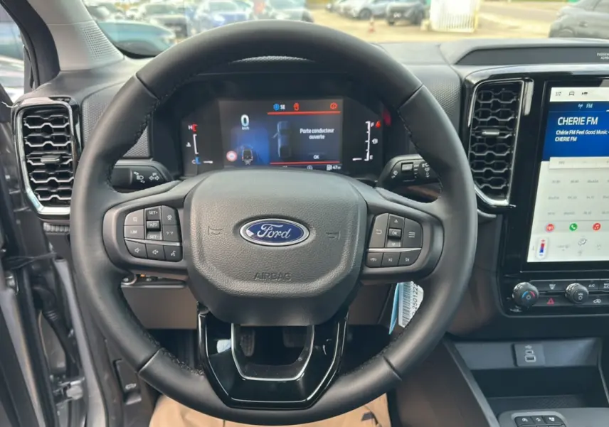 Vue rapprochée du volant cuir multifonctions du Ford Ranger gris iconic avec tableau de bord digital et écran tactile central.