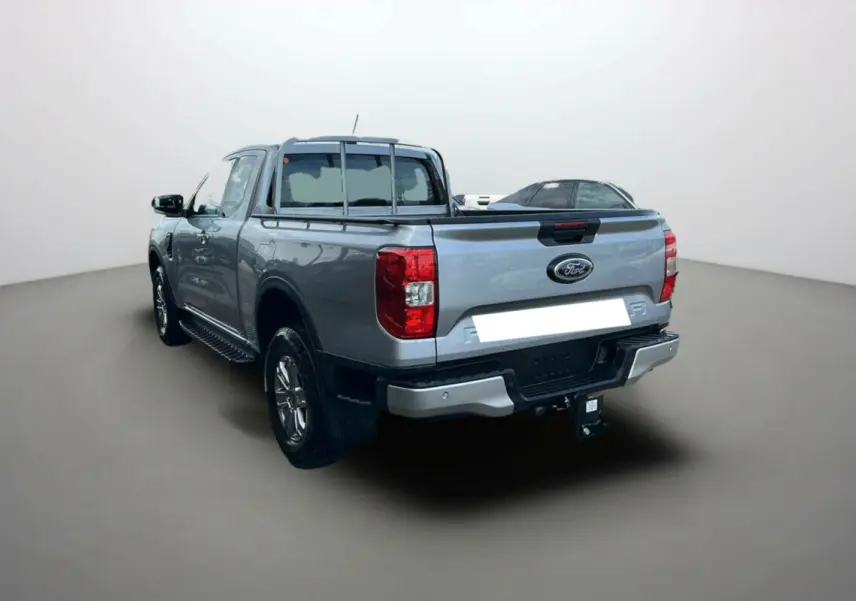 Vue 3/4 arrière gauche du Ford Ranger gris iconic avec attelage et marchepieds latéraux visibles.