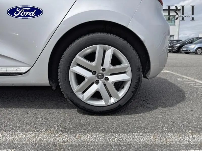 Gros plan sur la roue arrière droite d'une Renault Clio gris platine avec jante alliage à cinq branches.