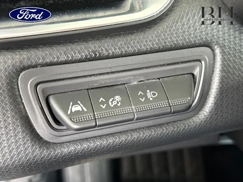 Boutons de réglage d'assistance et éclairage sur tableau de bord noir d'une Renault Clio gris platine, vue rapprochée.
