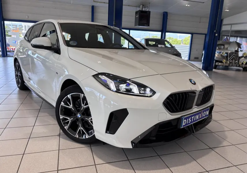 BMW Série 1 120d M Sport blanche vue en 3/4 avant droit, avec jantes noires et calandre noire distinctive.