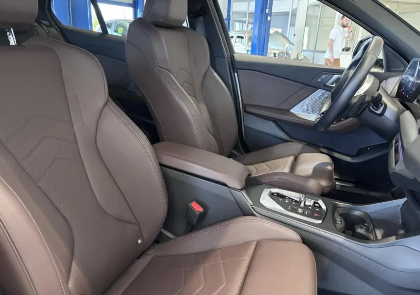 Intérieur de la BMW Série 1 120d M Sport 2025 vu côté droit, sièges en cuir marron et console centrale moderne.