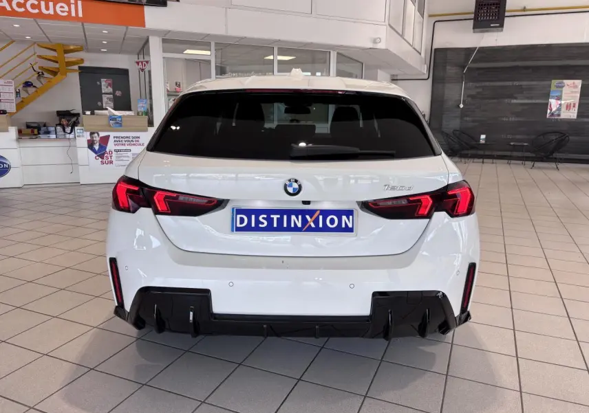 Vue arrière d'une BMW Série 1 120d M Sport blanche de 2025, avec feux arrière LED et diffuseur noir sportif.