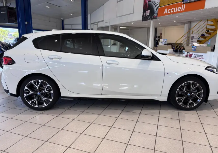BMW Série 1 120d M Sport blanc vue de profil côté gauche en intérieur, avec jantes alliage noires et détails M Sport.