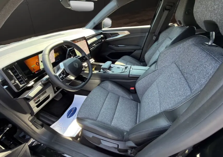 Vue intérieure côté conducteur de la Renault Rafale 2025 hybride, sièges gris tissu avec inserts cuir et tableau de bord digital.