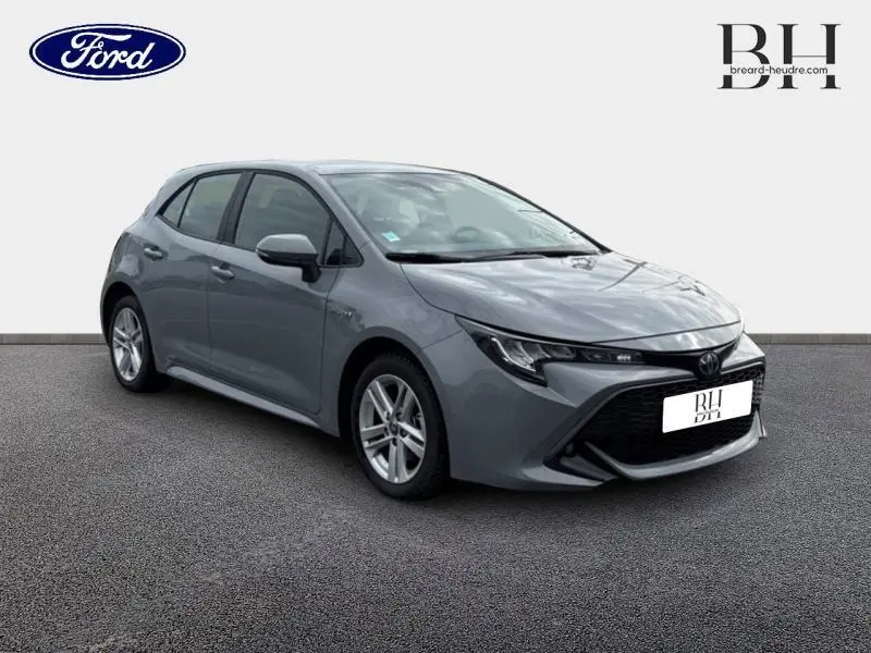 Toyota Corolla 122h Dynamic Business 2020 en gris Manhattan métallisé, vue 3/4 avant avec calandre noire distinctive.