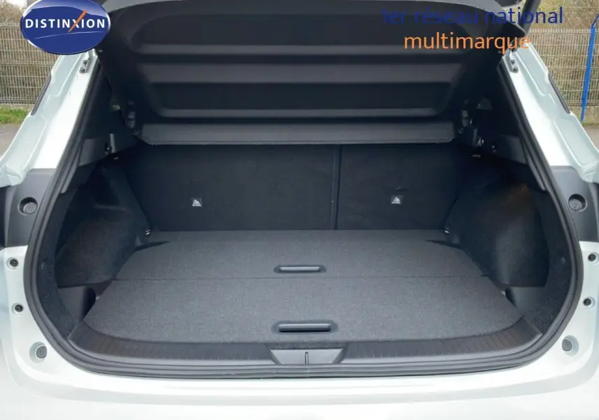 Coffre ouvert du Nissan Qashqai blanc nacré, montrant un espace de chargement plat et spacieux.