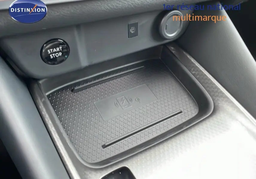 Gros plan sur la console centrale noire du Nissan Qashqai 2025, avec zone de charge sans fil et bouton start/stop visible.