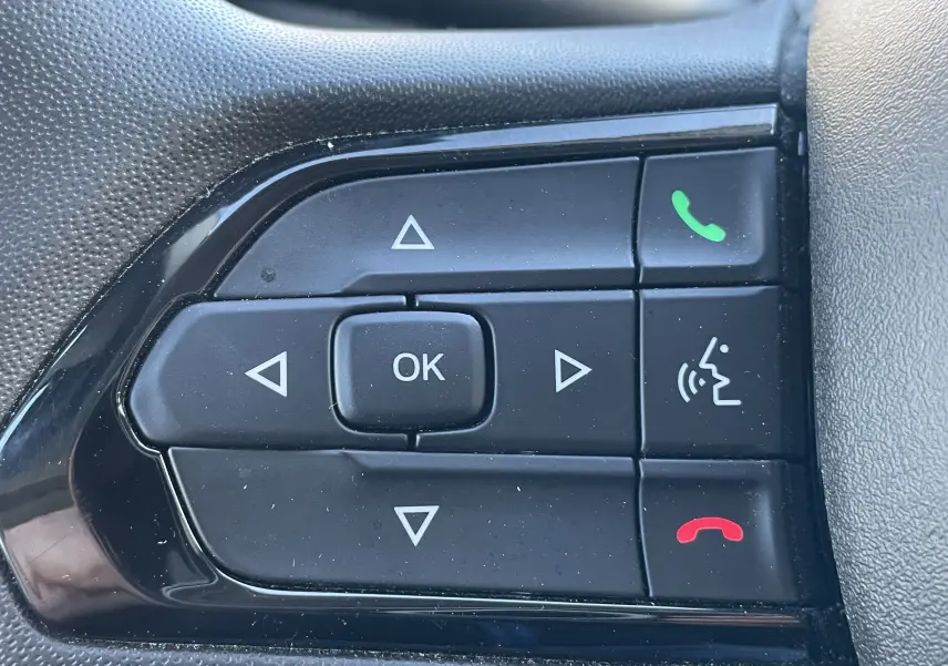 Gros plan sur les commandes noires du volant du Peugeot Boxer Fourgon blanc, boutons de navigation et appels téléphoniques.