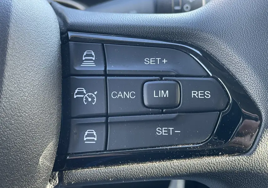 Gros plan sur les boutons de régulateur et limiteur de vitesse sur le volant du Peugeot Boxer Fourgon blanc.