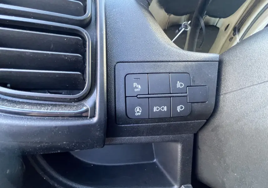 Gros plan sur les commandes de réglage des phares et aides à la conduite du Peugeot Boxer Fourgon blanc, intérieur côté conducteur.