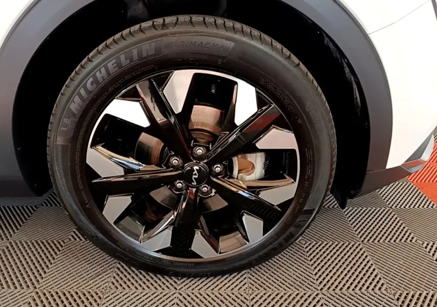 Gros plan sur la roue avant droite d’un KIA SPORTAGE blanc avec jante alliage noir et argentée brillante.