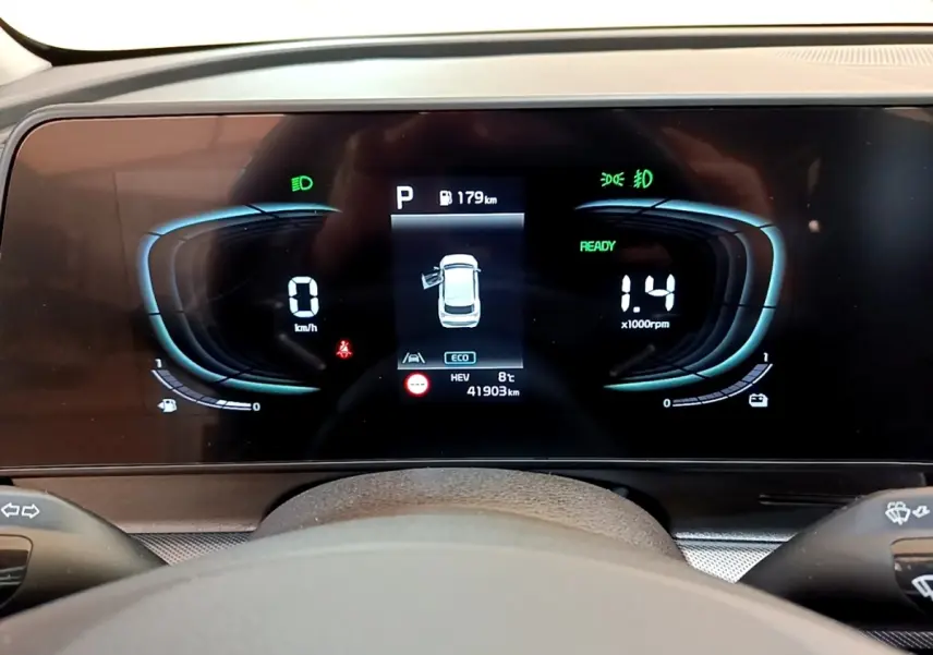 Tableau de bord numérique du Kia Sportage blanc, affichage central avec vitesse, régime et alertes visibles.