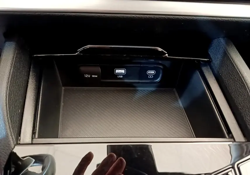 Vue rapprochée de la console centrale noire du Kia Sportage 2022 montrant les prises USB et 12V intégrées.