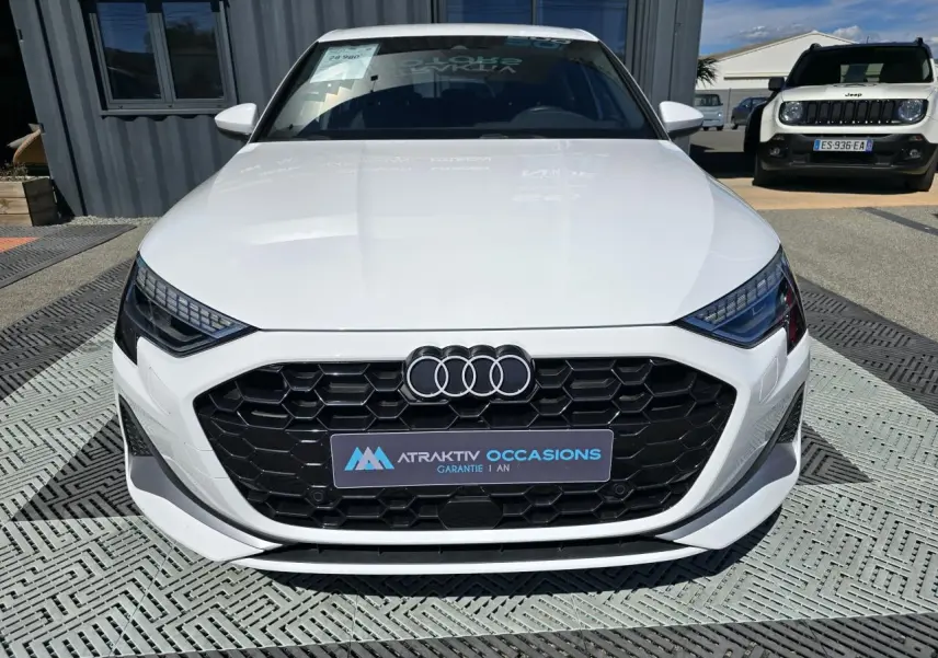Audi A3 Sportback blanc Arkona vue de face mettant en valeur la calandre noire hexagonale et les phares LED distinctifs.