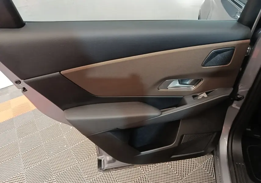 Vue intérieure de la porte arrière droite du DS7 Crossback gris foncé, avec garniture bicolore et poignée métallique.